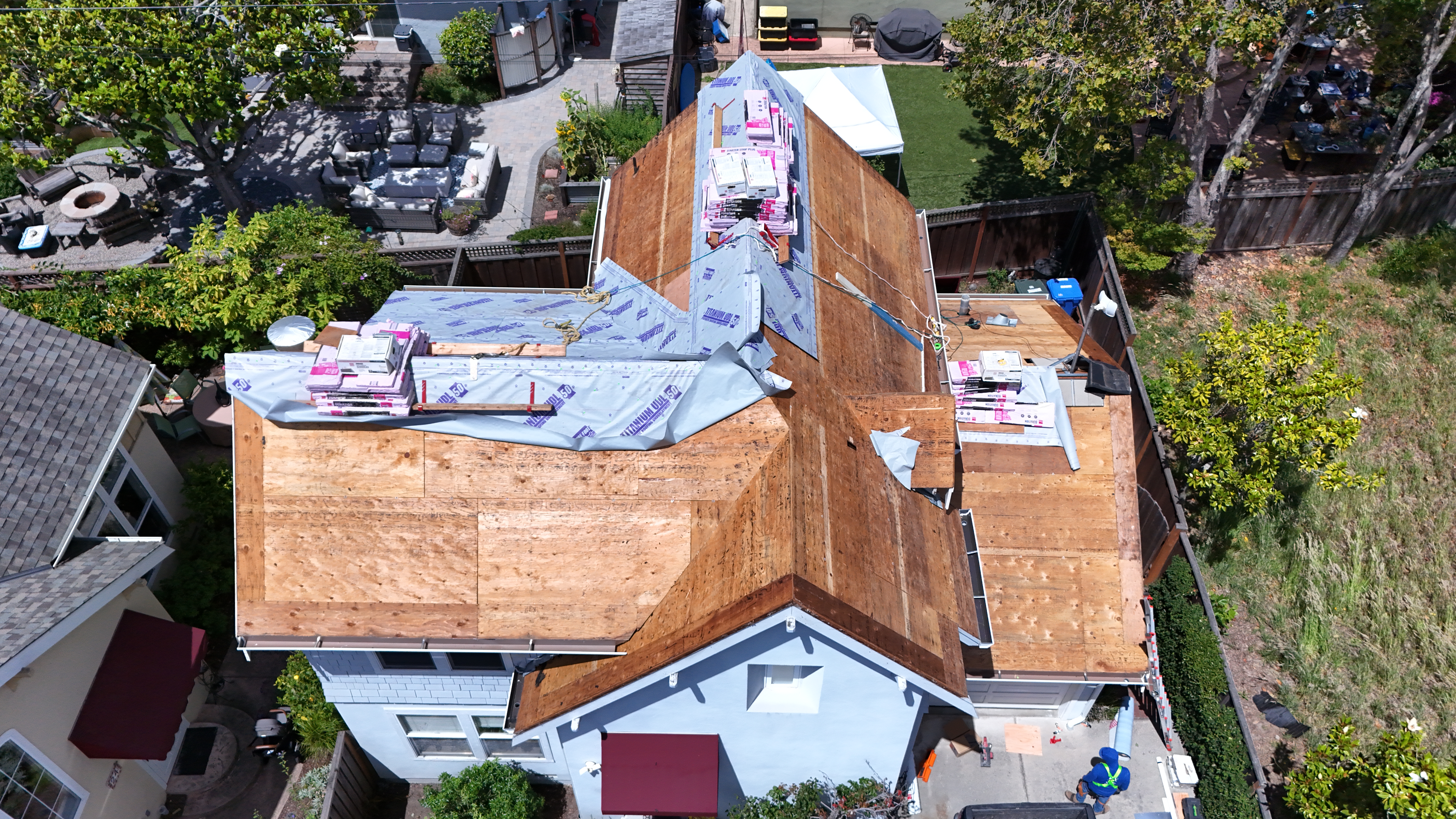 Overhead aerial of deck boards and underlayment with shingle bundles ready